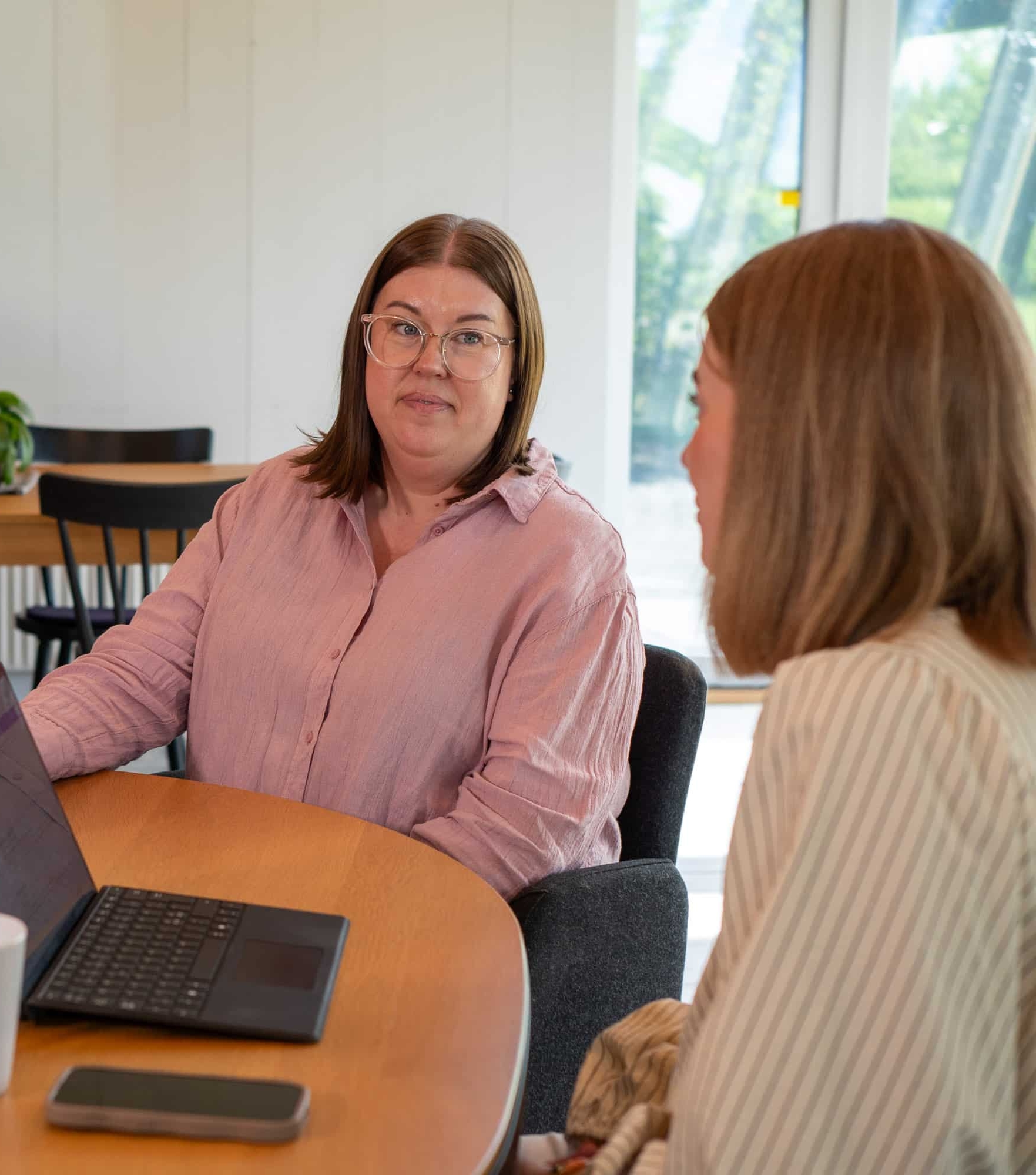 Person i professionellt samtal vid skrivbord – symboliserar löneförhandling
